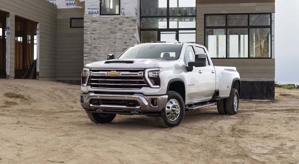 A white 2024 Chevy Silverado 3500HD LTZ is shown in front of a house being built.
