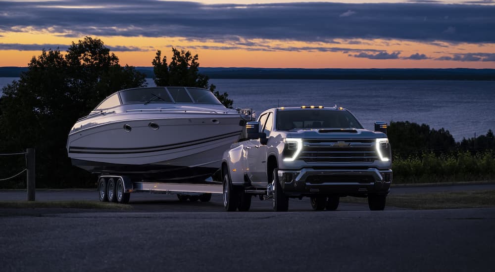 A white 2024 Chevy Silverado 3500HD LTZ is shown towing a boat after leaving a Chevy truck dealer near you.