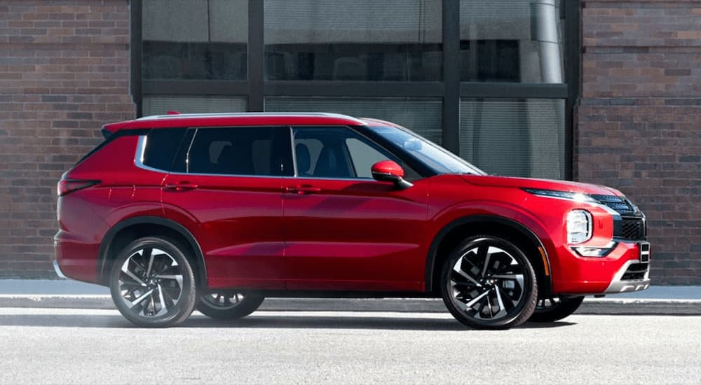 A red 2022 Mitsubishi Outlander for sale is shown from the side on a city street.