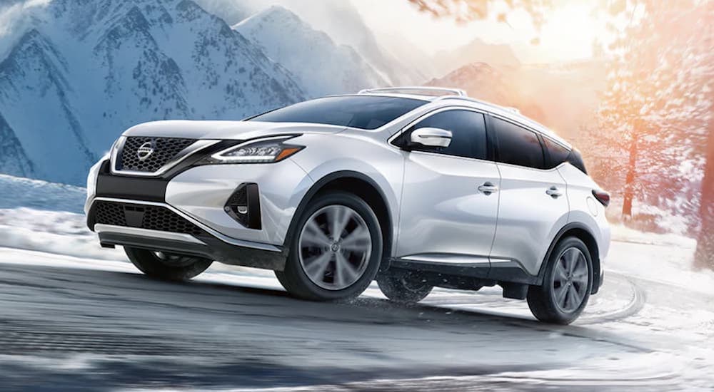 A white 2021 Nissan Murano is shown from the front at an angle on a snowy road after leaving a dealer that had a Nissan Murano for sale.