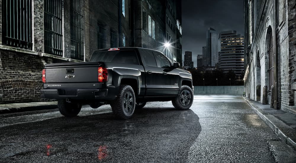 A black 2015 Chevy Silverado 1500 LT Midnight Edition is shown from behind on a city street at night.