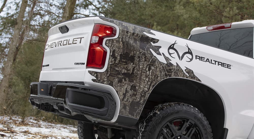 A close up shows the badging on the bed of a white 2021 Chevy Silverado 1500 Custom Realtree Edition.