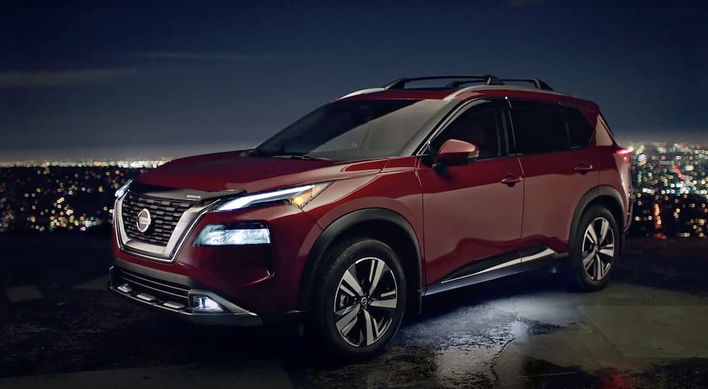 A certified used Nissan near you, a red 2021 Nissan Rogue, is shown from the side parked at night.