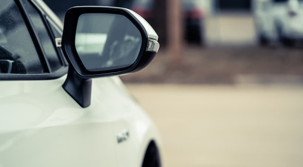 A close up of the mirror on a white vehicle is shown.