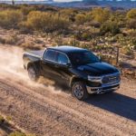 A black 2020 Ram 1500 truck for sale is shown driving on a dirt road.