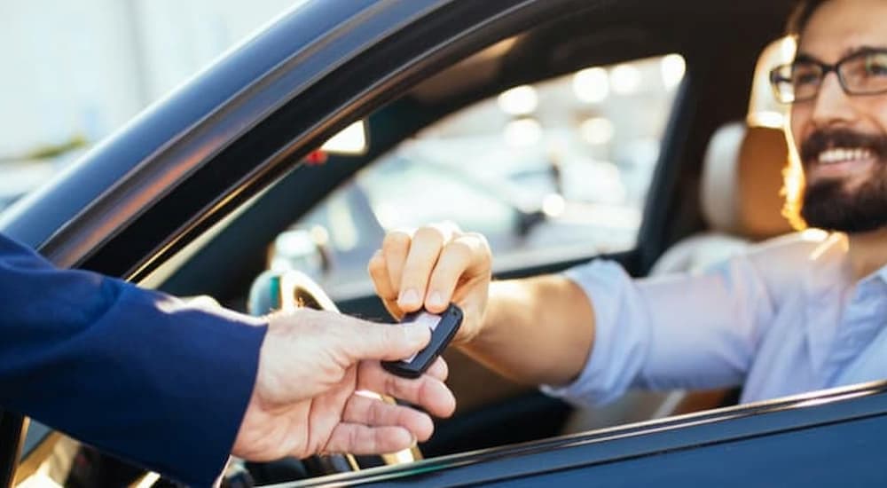 A salesman is shown handing a key to a customer.