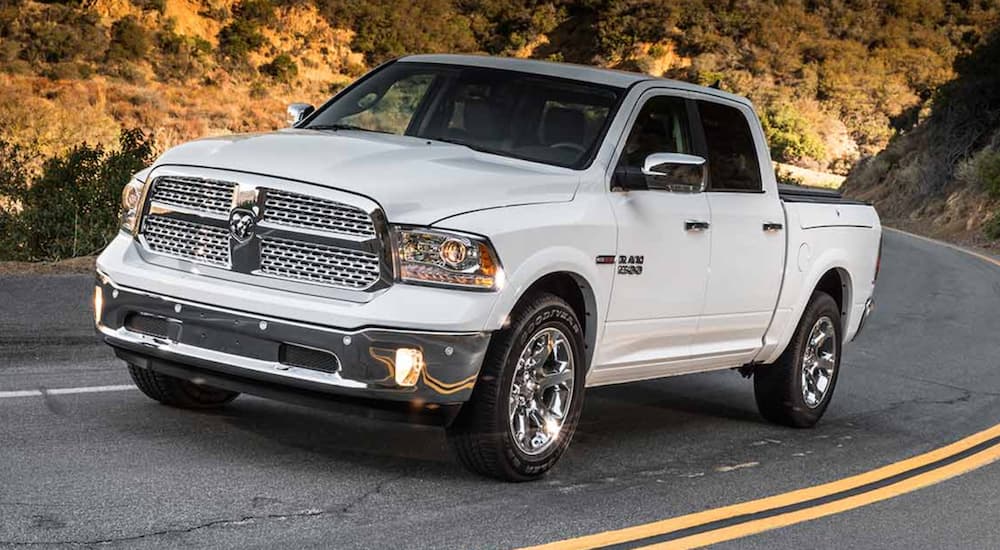 A white 2012 Ram 1500 is shown from the front at an angle after leaving a dealer that had used trucks for sale.