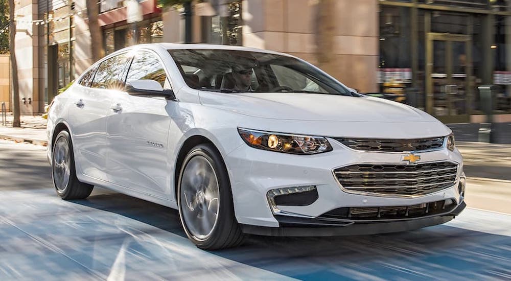 A white 2023 Chevy Malibu is shown from the front at an angle.