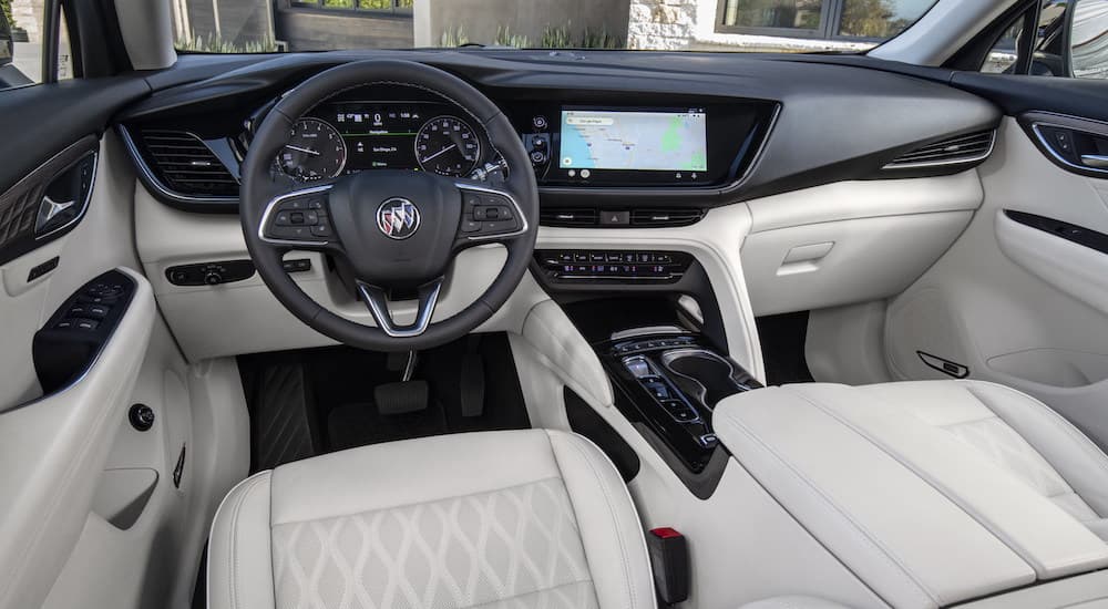 The white interior of a 2023 Buick Envision Avenir is shown from the drivers seat.