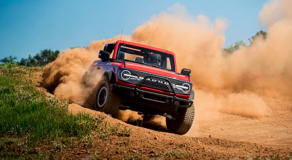 A red 2021 used Ford Bronco Badlands is shown from the front while driving off-road.