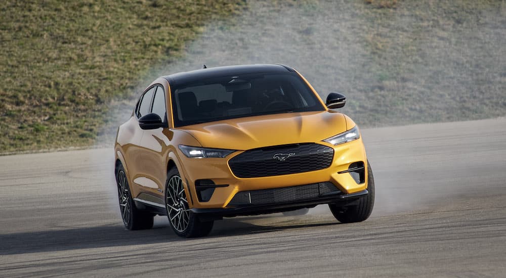 A yellow 2023 Mustang Mach E GT is shown from the front while sliding.