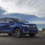 A blue 2023 Chevy Equinox is shown parked on a rocky coast.