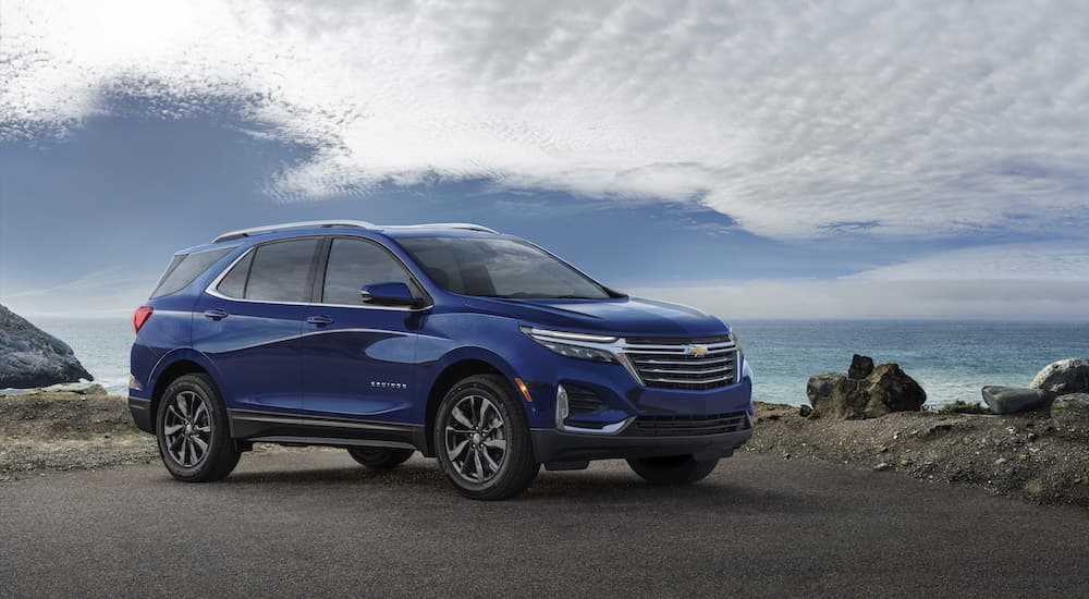 A blue 2023 Chevy Equinox is shown parked on a rocky coast.
