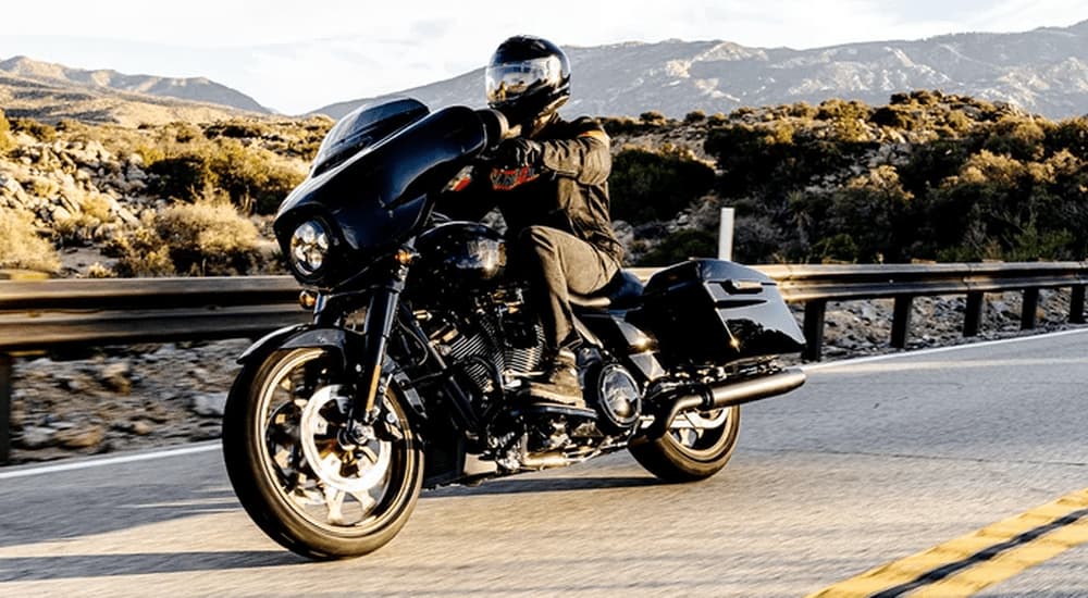 A man is shown on a 2022 Harley-Davidson Street Glide driving on an open road.