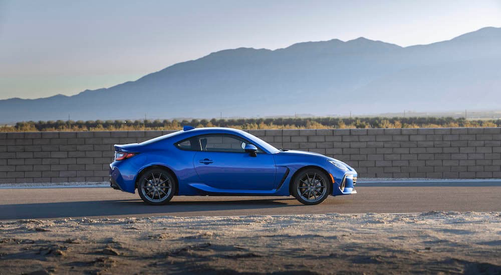 A blue 2022 Subaru BRZ is shown from the side in front of distant mountains.