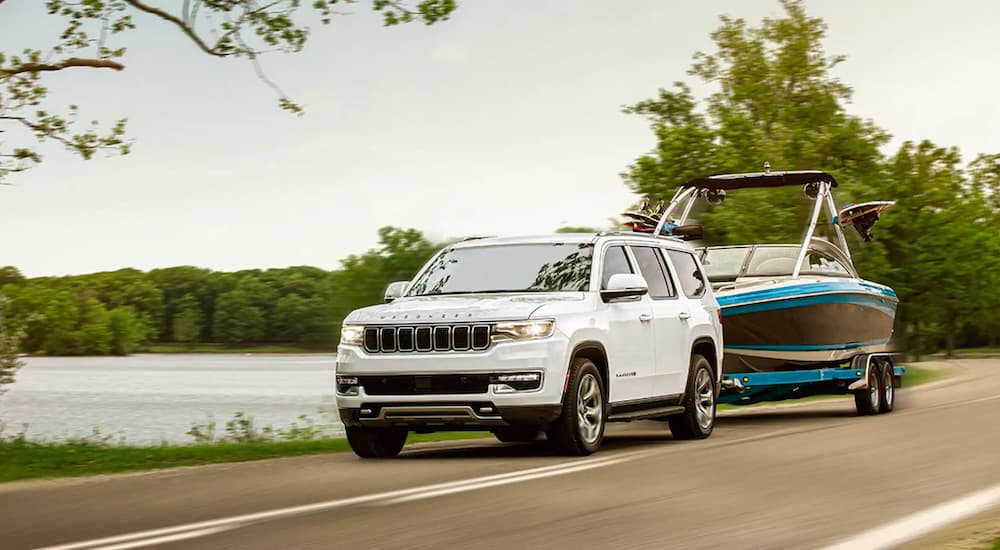 A white 2022 Wagoneer is shown towing a boat past a lake.