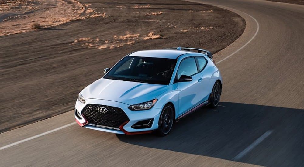 A light blue 2022 Hyundai Veloster N is shown from the front at an angle while rounding a corner.