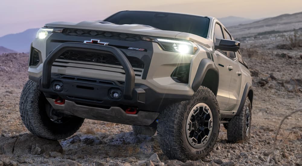 A tan 2023 Chevy Colorado ZR2 is shown parked in the mountains at sunset during a 2023 Chevy Colorado vs 2023 Jeep Gladiator comparison.