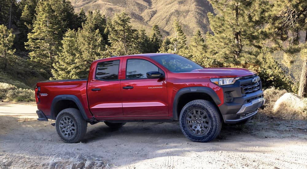 A red 2023 Chevy Colorado Trail Boss is shown driving on a dirt road.