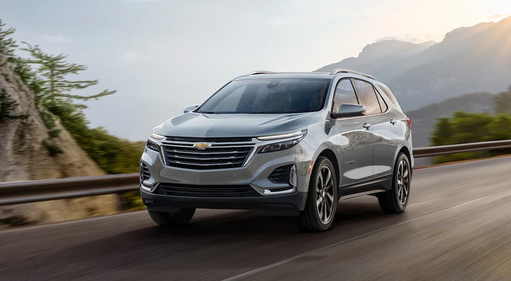 A 2023 Chevy Equinox is shown driving on an open highway through the mountains.