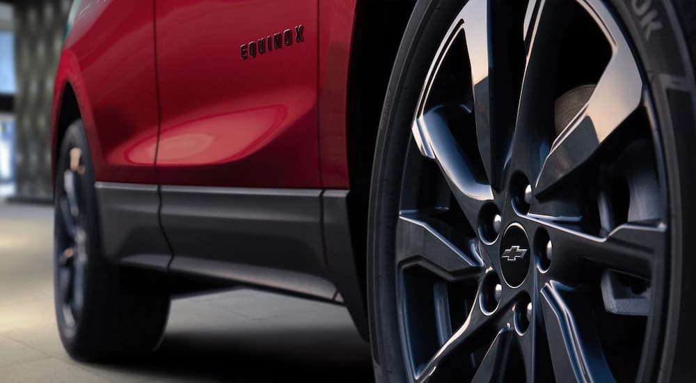 A close up of the rim and side of a red 2023 Chevy Equinox RS is shown.