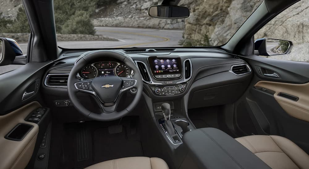 The black interior of a 2023 Chevy Equinox shows the steering wheel and infotainment screen.