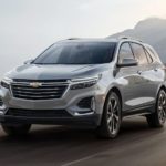 A grey 2023 Chevy Equinox is shown driving on an open road.