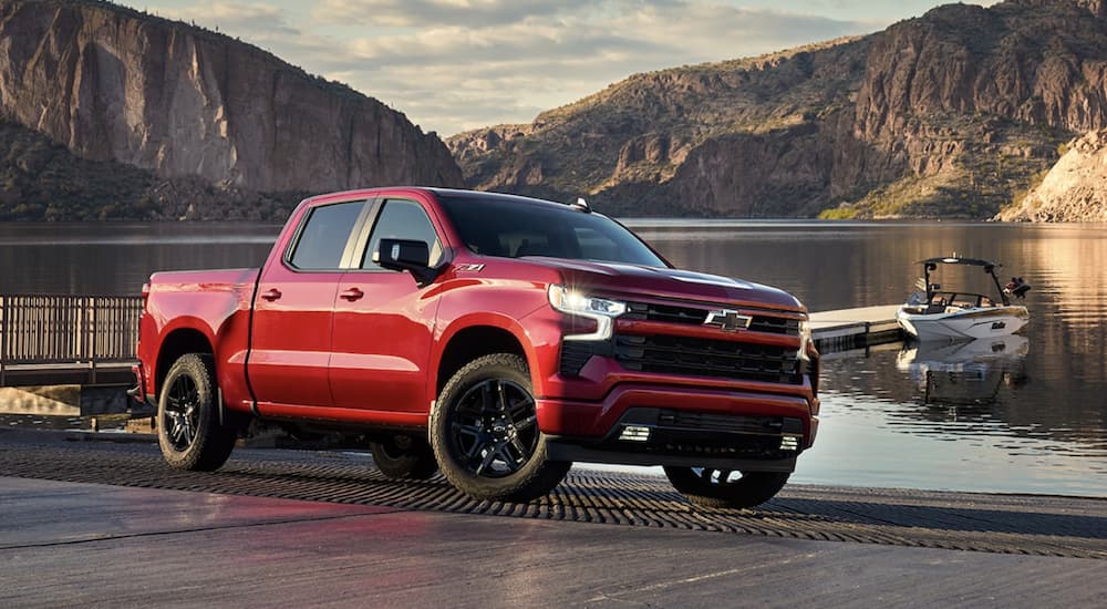 A red 2023 Chevy Silverado 1500 Z71 is shown from the side parked in front of a lake.