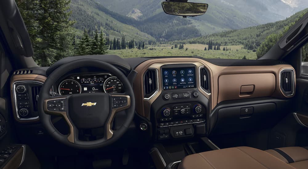The black and brown interior of a 2023 Chevy Silverado 3500HD shows the steering wheel and infotainment screen. 