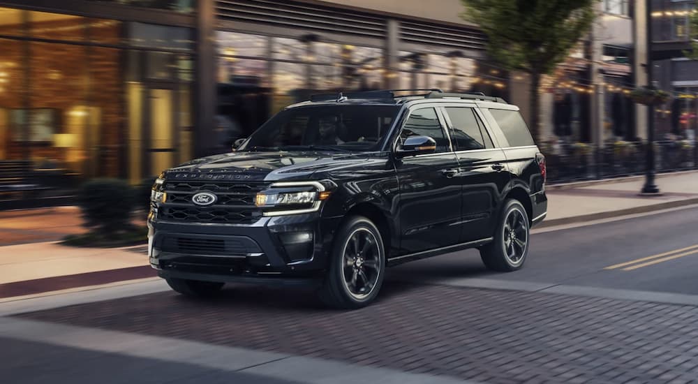 A black 2023 Ford Expedition is shown driving on a city street.