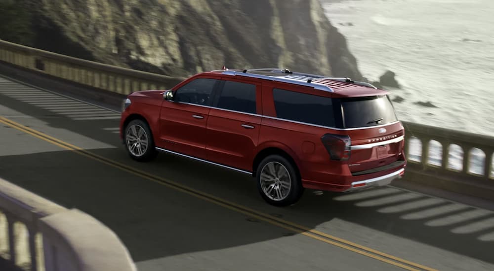 A red 2023 Ford Expedition is shown driving over a bridge.