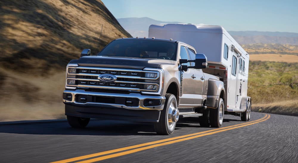 A grey 2023 Ford F-350 Super Duty is shown from the front at an angle while towing a camper.