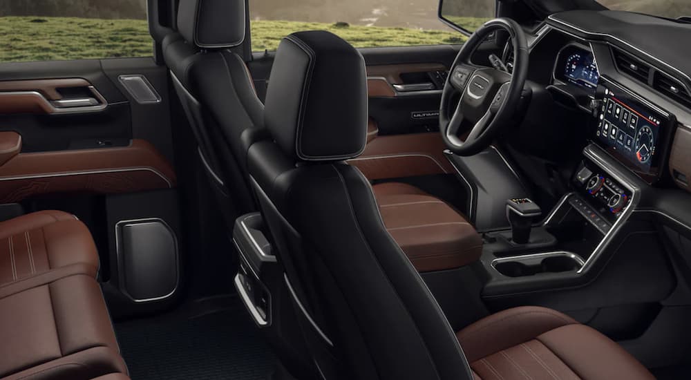 The black and brown interior of a 2023 GMC Sierra 1500 Denali shows two rows of seating.