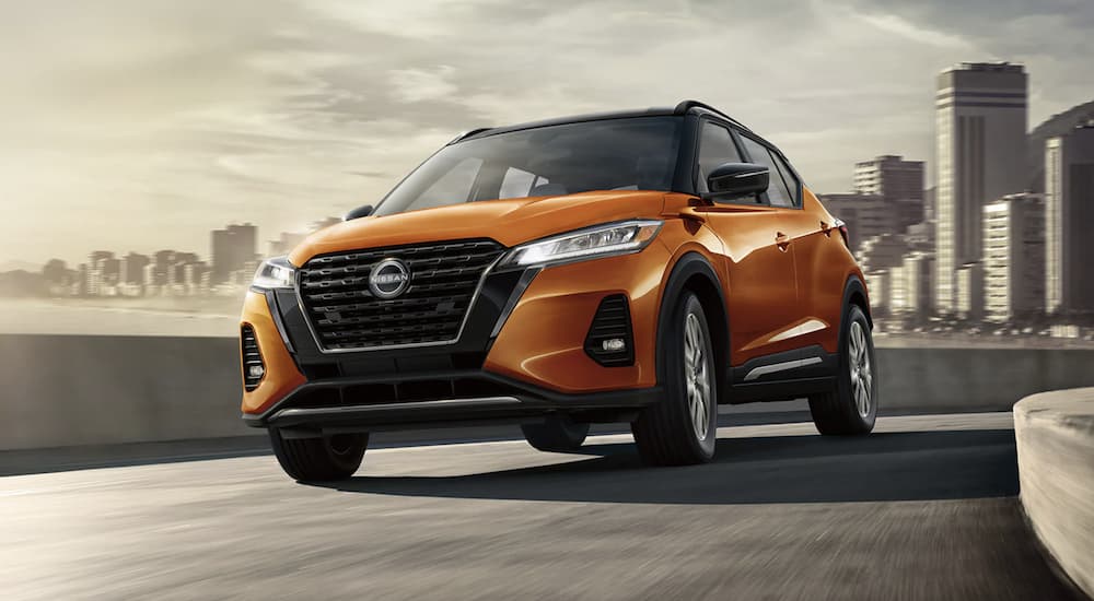 An orange 2023 Nissan Kicks is shown leaving the city.