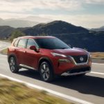 A red 2023 Nissan Rogue Platinum is shown driving on a mountain road.