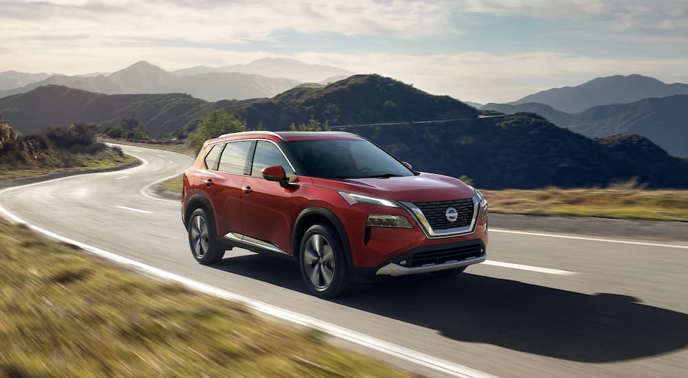 A red 2023 Nissan Rogue Platinum is shown driving on a mountain road.