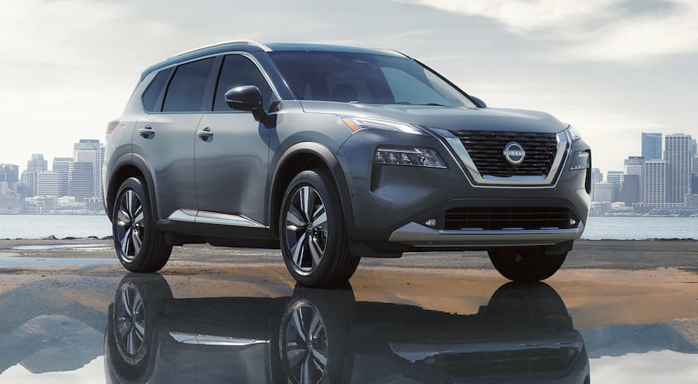 A grey 2023 Nissan Rogue is shown parked outside of a city.