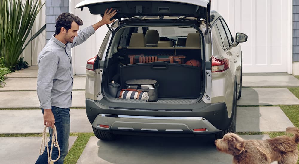 A tan 2023 Nissan Rogue is shown with the trunk open.