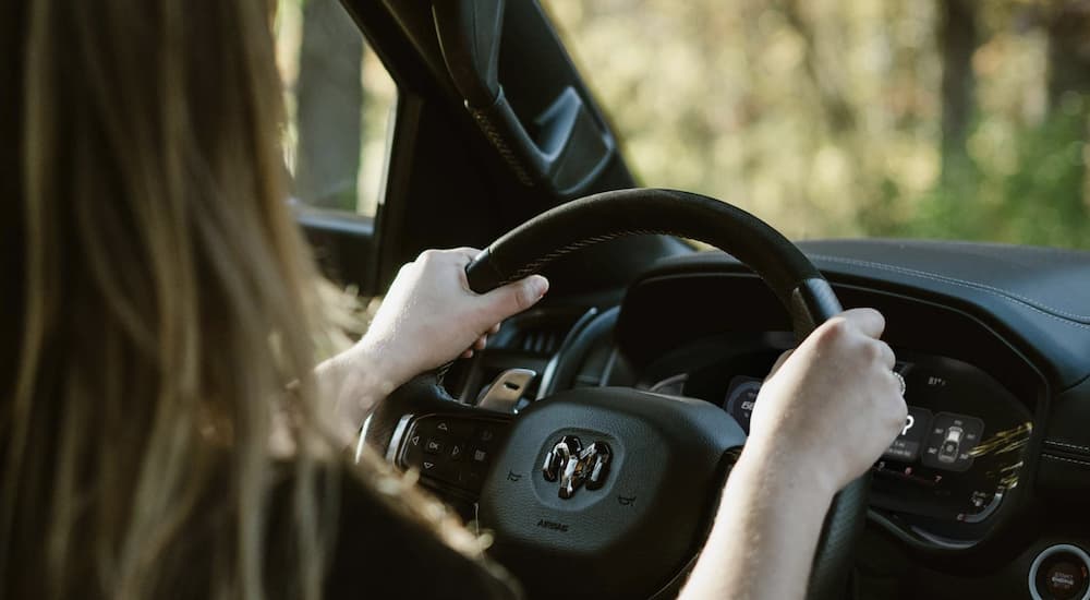 The black interior of a 2023 Ram 1500 TRX shows a person driving.