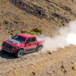 A red 2023 Ram 1500 TRX is shown off-roading in the desert.