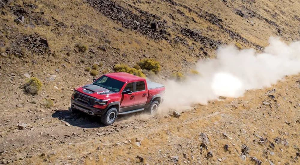 A red 2023 Ram 1500 TRX is shown off-roading in the desert.