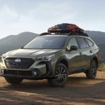 A green 2023 Subaru Outback Onyx Edition XT is shown parked in front of a mountain range.