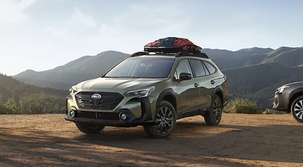 A green 2023 Subaru Outback Onyx Edition XT is shown parked in front of a mountain range.