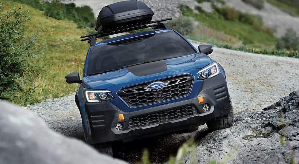 A blue 2023 Subaru Outback Wilderness is shown parked on a rock.
