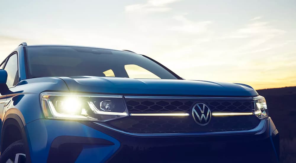 A close up shows the headlights and grille on a blue 2023 Volkswagen Taos.