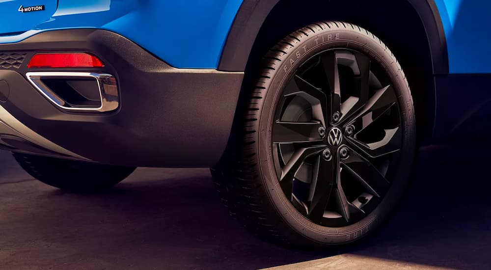 A close up shows the black wheel on a blue 2023 Volkswagen Taos.