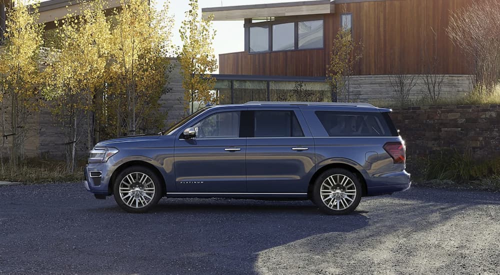 A blue 2023 ford Expedition is shown parked in front of a modern home.