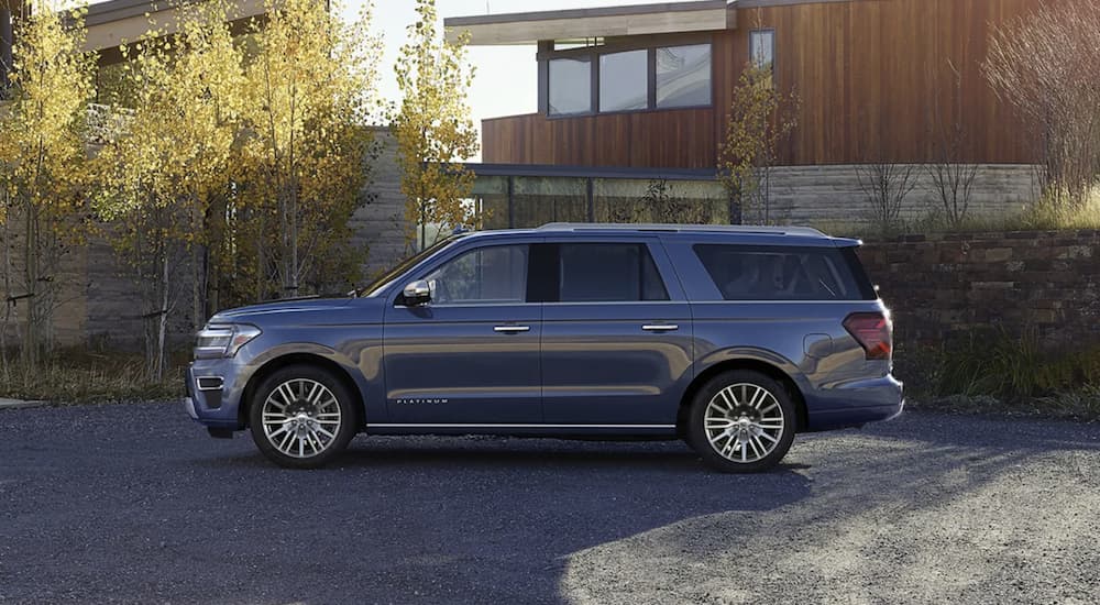 A blue 2023 Ford Expedition is shown from the side parked in front of a modern house.