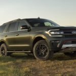 A green 2023 Ford Expedition is shown parked on a grass field.