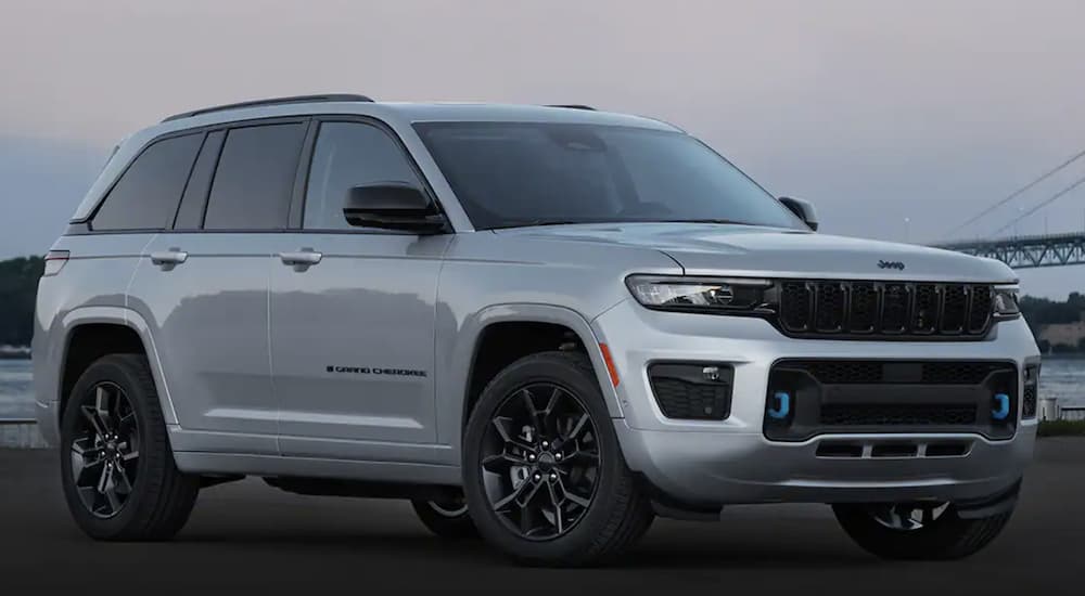 A grey 2023 Jeep Grand Cherokee 4xe is shown from the side parked on a beach.